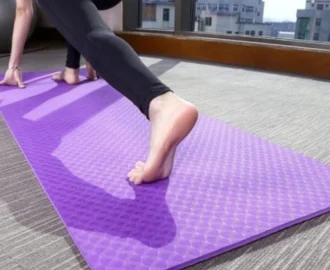 A thick, textured purple yoga mat placed on a carpeted floor A thick, textured purple yoga mat placed on a carpeted floor