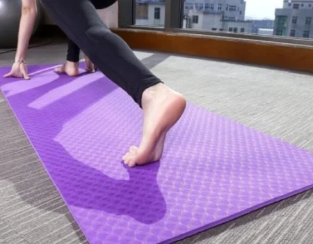 A thick, textured purple yoga mat placed on a carpeted floor A thick, textured purple yoga mat placed on a carpeted floor