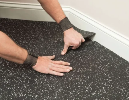 Installing the black speckled rubber mats in a corner with white baseboard Installing the black speckled rubber mats in a corner with white baseboard
