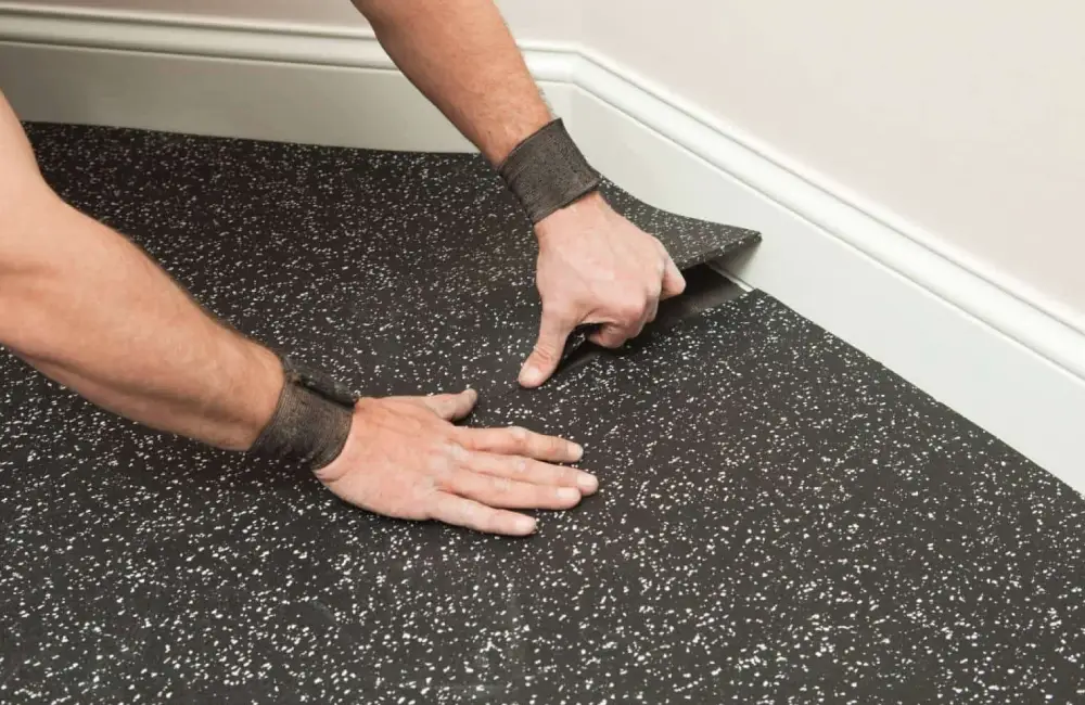 Installing the black speckled rubber mats in a corner with white baseboard Installing the black speckled rubber mats in a corner with white baseboard